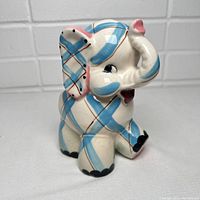 Side view of vintage ceramic elephant planter showing blue gingham check pattern and pink accents on trunk and ear tip.