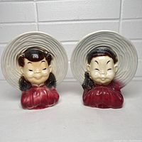 Pair of vintage Royal Copley Asian couple ceramic wall planters wearing large straw hats and red garments, showing front views of both boy and girl planters.