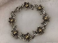 Bracelet laid out circularly showing flower design with yellow gold ball centers.
