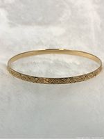 front view of slim gold bangle on white background