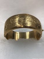 Front view of hinged bangle showing engraved scrollwork and heart motifs.