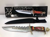 Photo showing the knife in its box with sheath below it, highlighting blade design and handle colors.