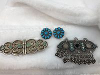 Sterling silver Navajo native earrings and two collar brooches on white background to show overall lot contents