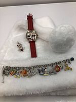 Disney charm bracelet, Minnie pendant, and Mickey & Minnie watch displayed on white surface.