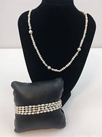Fresh water pearl necklace displayed on black bust with 4-strand pearl bracelet on black cushion below