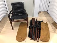 One assembled chair with disassembled second chair components and two tan canvas storage bags