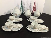 Complete tea set arranged showing teapot, sugar bowl, creamer, and 4 tea cups with saucers