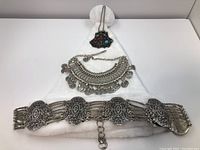 Full view of tribal coin necklace and 925 silver ornate belt with coin pendant on white cloth.