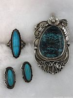Full set including pendant, ring, and earrings on white fur background.