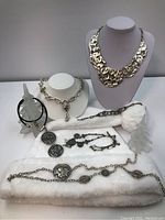 Full lot overview showing all five jewelry pieces on two display stands and fabric surface.