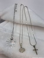 Three sterling silver necklaces with pendants including a clear crystal snowflake pendant, and two cross pendants - one marcasite and amethyst accented, the other plain.
