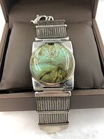 Close up front view of silver mesh bracelet with large round turquoise centerpiece stone set in silver mounting.