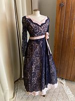Full view of vintage 1950s black lace dress over pink fabric on mannequin showing full length and lace detail
