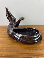Side and angled view showing the shape, details of the wings, and interior basin of the goose planter.