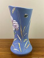 Blue pottery vase with raised floral trillium design on one side, vertical view.