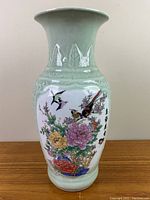 Front and body view of the green glazed Chinese vase with colorful birds and flowers motif and Asian writing on white background.