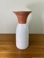 Front view of the pottery vase showing the terracotta top and white ribbed glaze body.