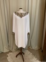 Full front view of the cream gown on a dress form showing the entire garment and undecorated body of the dress.