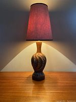 MCM ceramic genie bottle lamp illuminated indoors; shows lamp lit with a reddish hue through the shade and visible texture/details on ceramic base