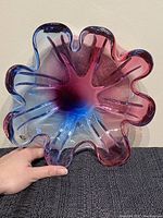 Top view of the art glass dish showing the flower-like ruffled edges with gradient colors from purple to blue to pink.