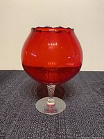 Front view of the ruby red glass snifter with ruffled rim and clear twisted stem