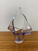 Clear and light purple art glass dish viewed from front angle, showing basket shape with a loop handle.