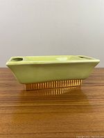 Front side view of green rectangular ceramic planter showing the ribbed base and two grill-like openings on the rim.