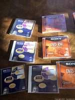Photo of blank DVDs and CDs including Sony and Hewlett Packard brands in original sealed packaging on a wooden surface.