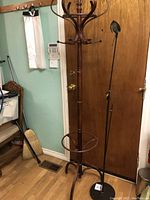 Full view of the wooden coat rack showing multiple hooks and circular umbrella holder near the middle.