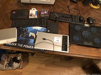Overview photo of lot including two keyboards, mouse, mouse pad, HDMI cable, reel clips, black external drive, laptop cooler, and cables.