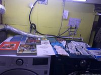 Overview of emergency and first aid supplies along with medical books displayed on a table in front of laundry machines.