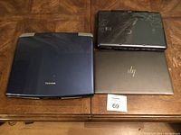 Top view of three laptops closed, showing different colors and logos: Toshiba, HP, and an unidentified laptop.