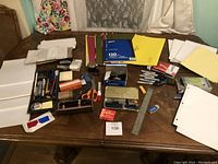 Wide view of all office supplies laid out on a table showing writing tools, papers, folders, and accessories.