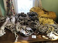 Overview of multiple coiled climbing ropes on table along with yellow carrying bag