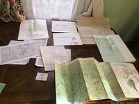 Overview of all Scouts maps spread on wooden surface showing varying sizes, some folded and some opened. Includes some paperwork and labels.