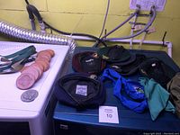 Photo showing Scouts hats (black, green, maroon), green neckerchief, round coins, and patches on a table with yellow background.