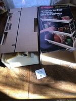 Boxed Rubbermaid Spacemaker adjustable bin & shelves set shown unopened in packaging alongside other boxes.