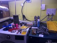 Full lot on top of washer and dryer showing all items including cords, sealant sprays, clamps, glue, fasteners, and trays.