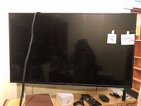 Front view of the 42-inch Insignia TV with cables and accessories on the surface below it.