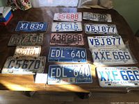 Full view of all 15 vintage British Columbia car license plates arranged on table.