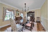 Full view of the dining room showcasing the rectangular Ethan Allen cherry wood dining table with six chairs around it, two upholstered with floral fabric, the rest wooden with cushions, situated near windows in a formal dining room.