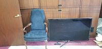Front view of one blue upholstered dining room wing end chair next to a flat screen TV for scale