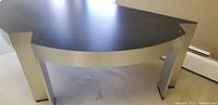 Side angle of the modern style semi-circular desk showing the dark tabletop and metallic legs