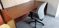 Office desk with cherry wood finish, showing top and part of side. Features two circular cable holes for wire management.