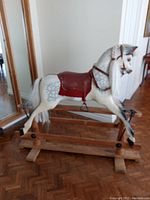Full side view of the carved wood rocking horse on wooden trestle base