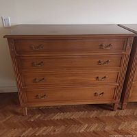 Full view of the chest showing four drawers, brass handles, and carved decorative details.