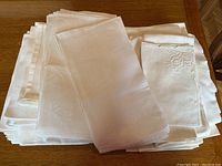 Stack of white linen napkins showing both folded and stacked pieces on a wooden table.