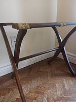 Side view of wood folding luggage rack showing curved legs and horizontal support bars.