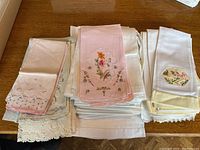 Three stacks of hand towels on wooden surface showing variety of embroidery and trims