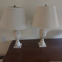 Pair of alabaster urn form lamps on wooden surface